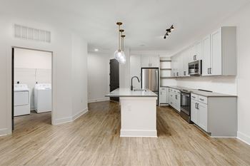 A modern kitchen with white appliances and wooden floors.